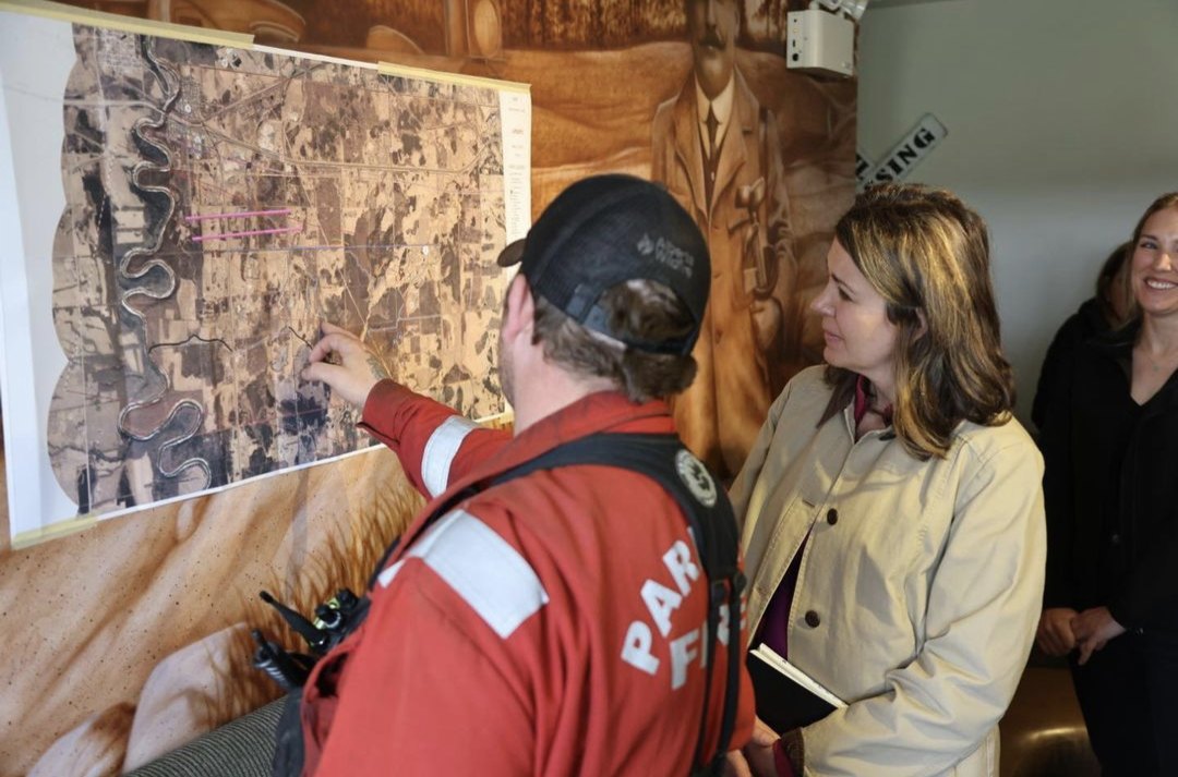 Sean briefing visiting leaders over a wall map of a wildfire area